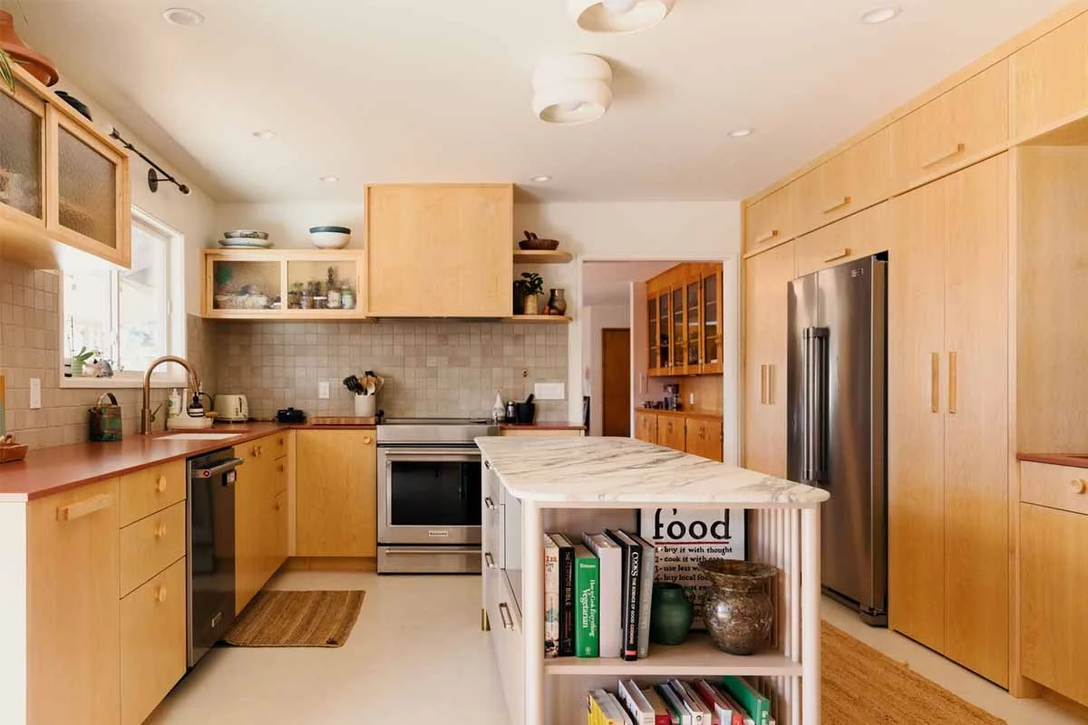 Warm-toned kitchen with maple flat-front cabinets, marble island, and stainless steel appliances by RnD Builders Inc