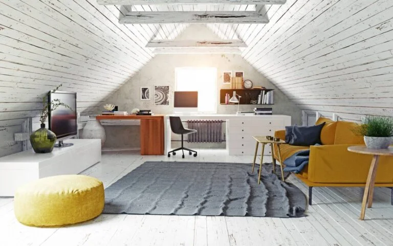 Attic conversion home office with vaulted whitewashed wood ceiling, walnut desk, and mustard sofa by RnD Builders Inc