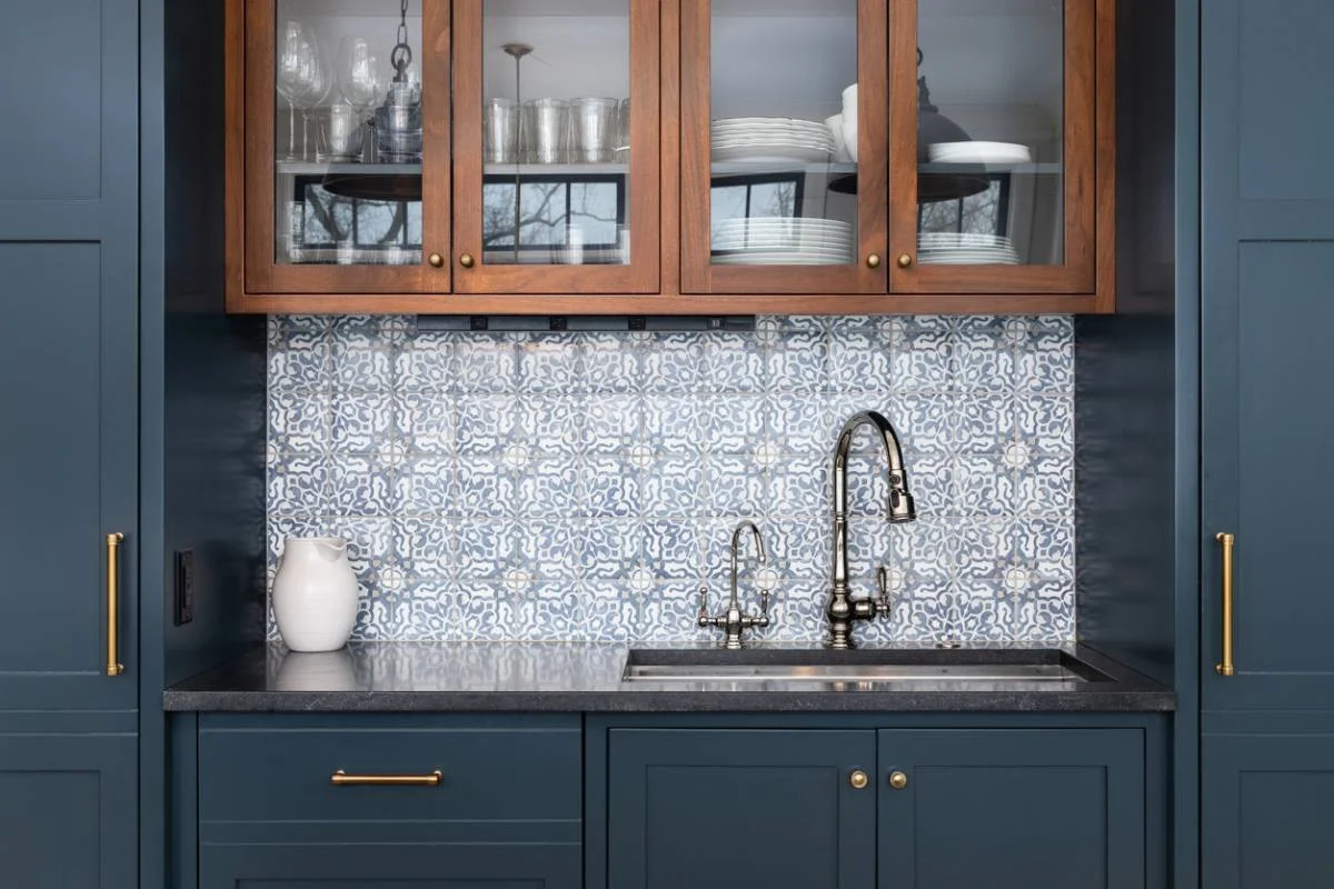 Butler's pantry with navy shaker cabinets, walnut glass-front uppers, and blue encaustic tile backsplash by RnD Builders Inc
