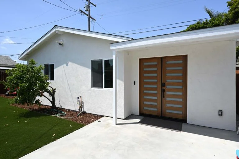 Modern white stucco ADU exterior with double wood and frosted glass entry doors by RnD Builders Inc