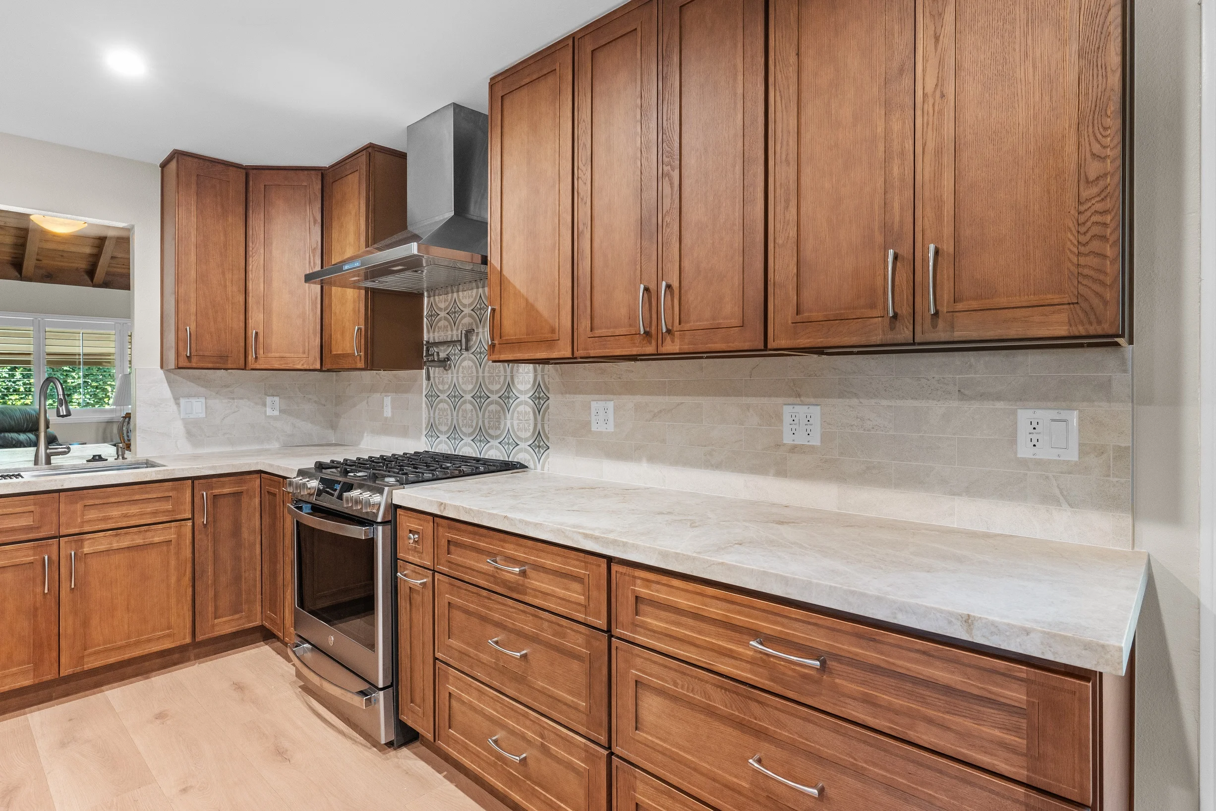 Traditional kitchen with warm wood shaker cabinets, quartz countertops, stainless range, and decorative tile backsplash by RnD Builders Inc