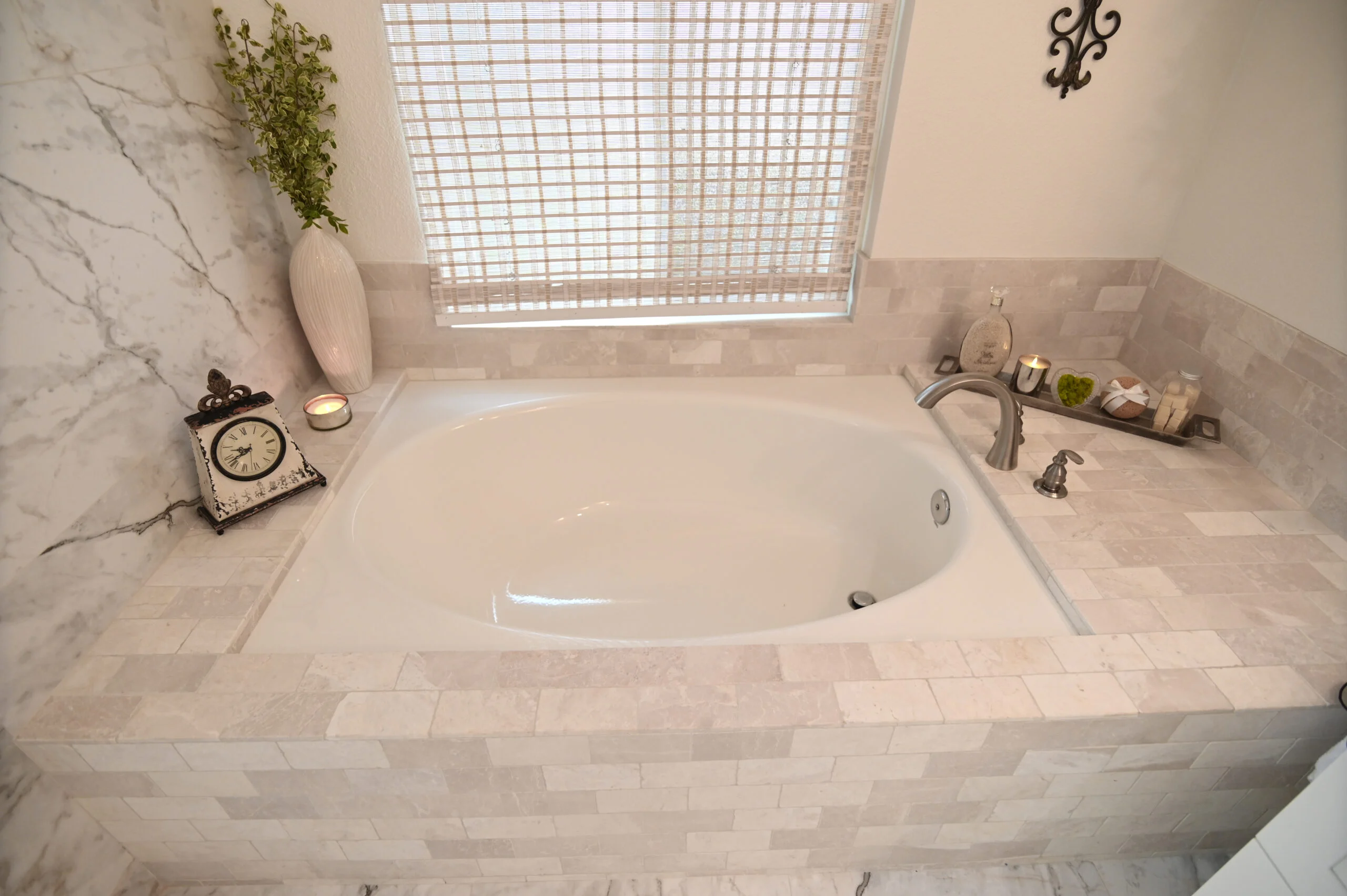 Drop-in soaking tub with travertine tile surround and brushed nickel faucet by RnD Builders Inc