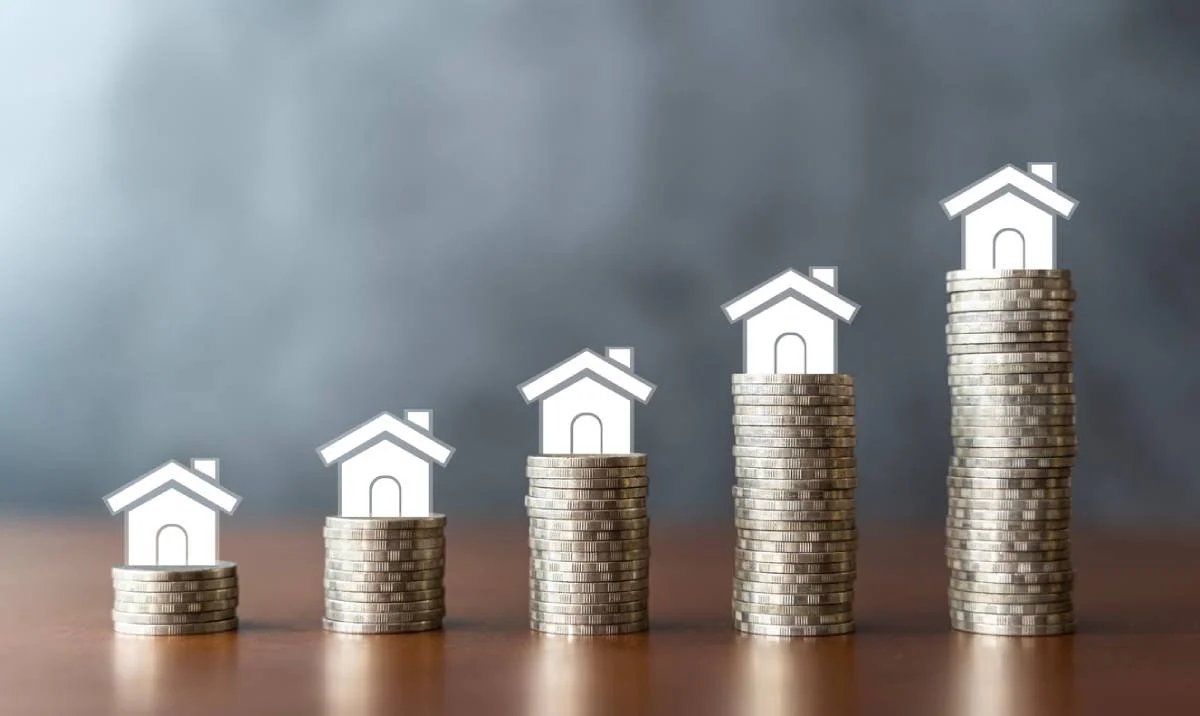 Graphic illustration of five growing coin stacks topped with white house icons representing increasing home value by RnD Builders Inc