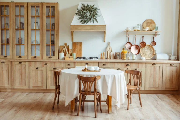 Warm farmhouse kitchen with natural wood cabinetry, gas cooktop, and round dining table by RnD Builders Inc