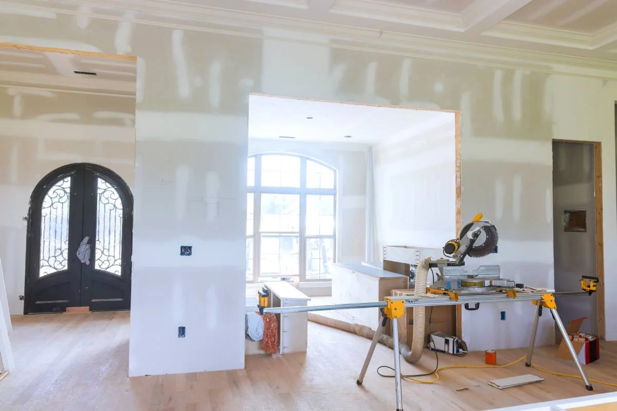 Home interior under construction with drywall, arched entry door, and miter saw by RnD Builders Inc