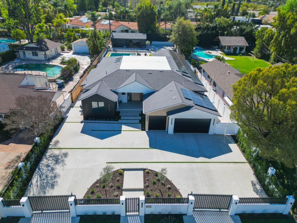 Aerial View of Modern Custom Home with Dark Siding Aerial view of modern custom home with dark siding, three-car garage, and pool by RnD Builders Inc