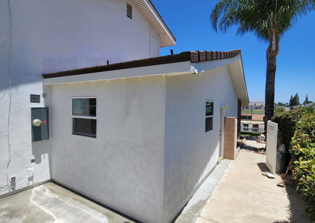 Exterior Stucco Room Addition with Dark Fascia Placentia bathroom addition: Exterior stucco room addition with dark fascia, dual windows, and concrete pathway in Placentia by RnD Builders Inc