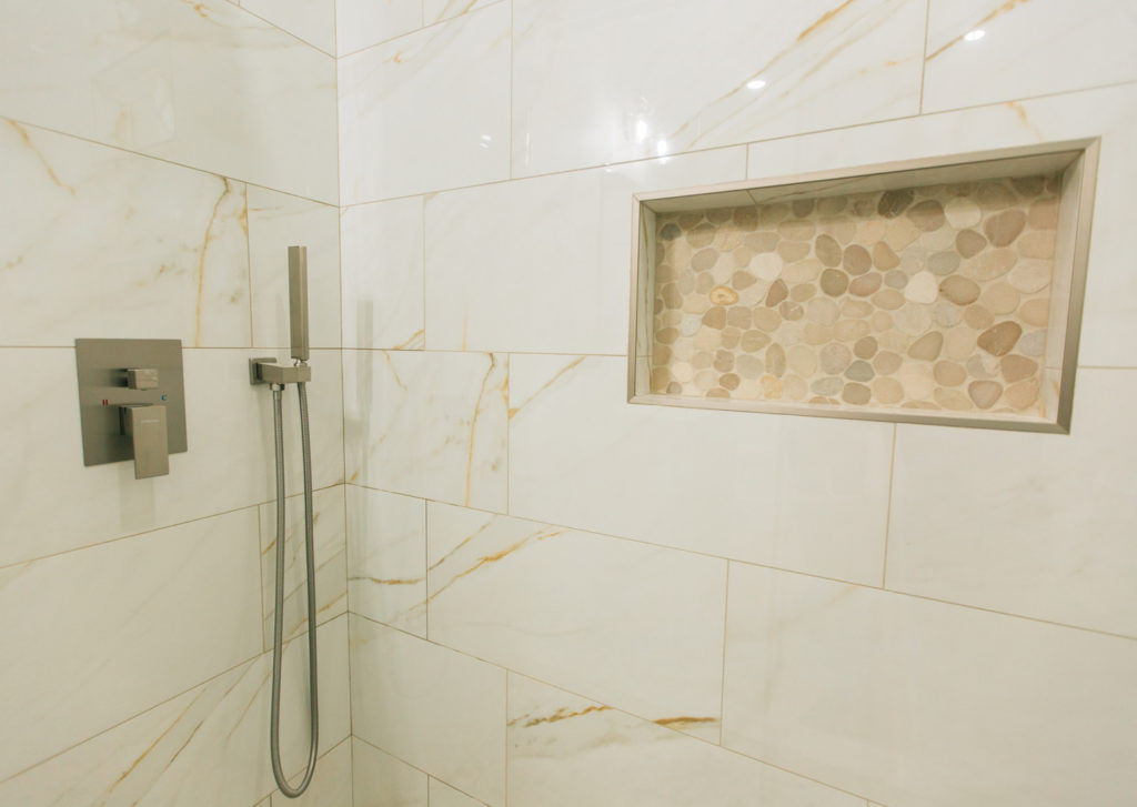 Echo Park interior remodel: Walk-in shower with large-format marble-look tile, pebble stone niche, and brushed nickel fixtures in Echo Park by RnD Builders Inc