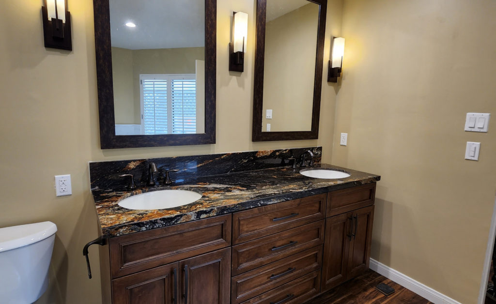 Double-sink Bathroom Vanity Double-sink bathroom vanity with dark granite countertop and raised-panel walnut cabinets by RnD Builders Inc