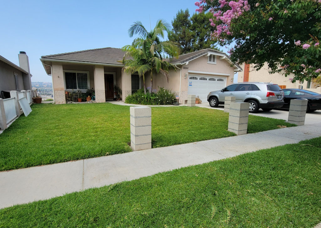La Puente exterior remodel: Single-story stucco home with tile roof, green lawn, and concrete pillar entry in La Puente by RnD Builders Inc