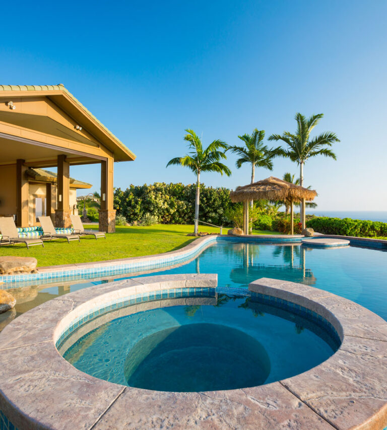 Luxury infinity pool with circular spa, teal mosaic tile, and ocean view by RnD Builders Inc