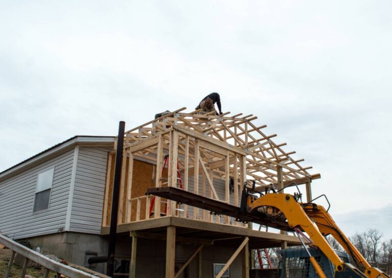 The image shows carpenters on the roof of new building addition. It supplements this guide to home additions in Los Angeles.