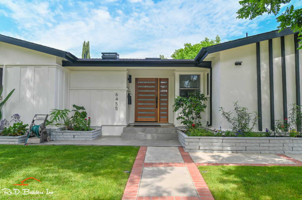 Woodlake home remodel: Mid-century modern home exterior with wood and glass horizontal-slat entry door and white stucco facade in Woodlake by RnD Builders Inc