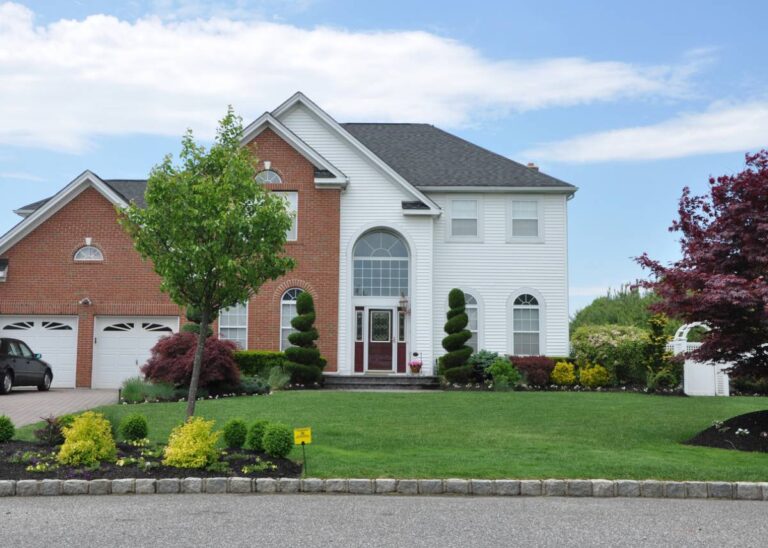 A large home featuring a well-maintained driveway and landscaped garden, showcasing a welcoming exterior.