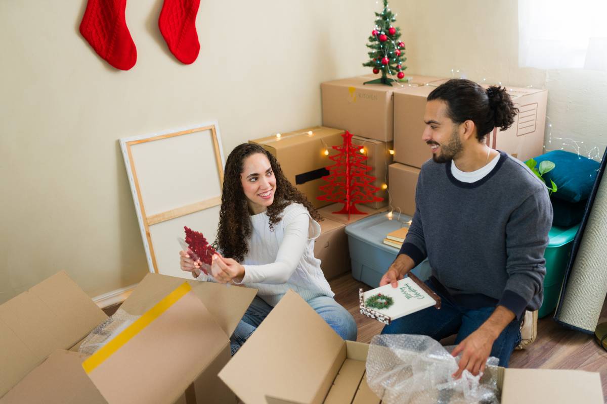 Young couple packing Christmas decorations in home.