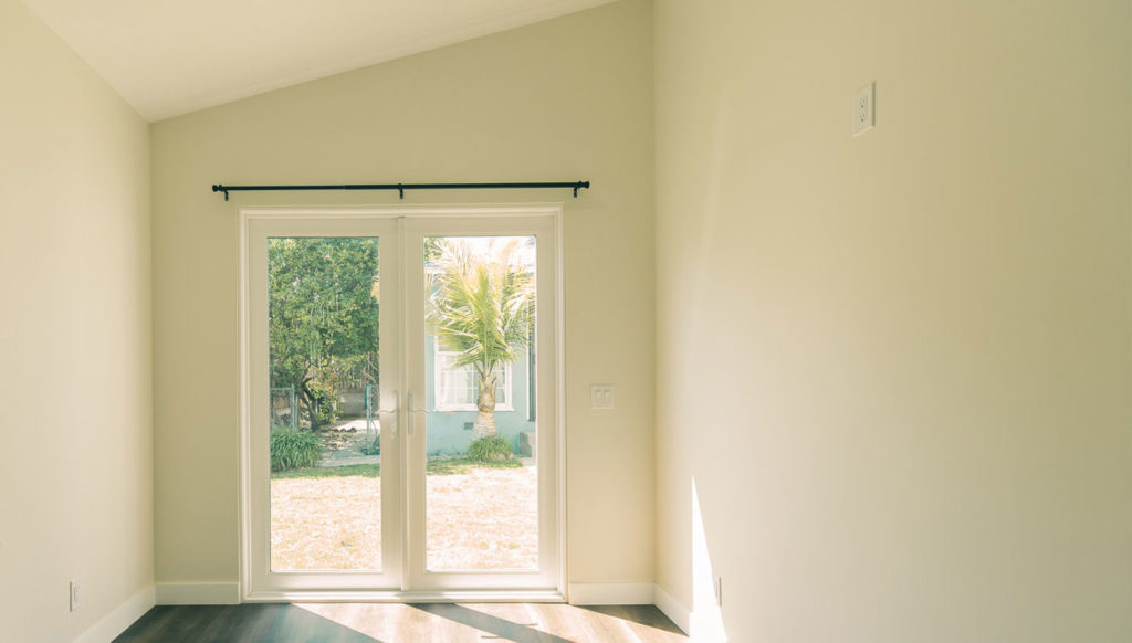 Empty Bright Room with White French Doors in Inglewood Empty bright room with white French doors, dark curtain rod, and dark hardwood flooring in Inglewood by RnD Builders Inc