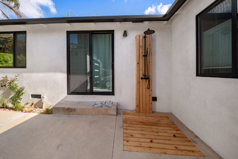 Outdoor Shower Beside Sliding Door with a wood-slat shower panel, a black-framed sliding door and a deck landing in Manhattan Beach by RnD Builders Inc