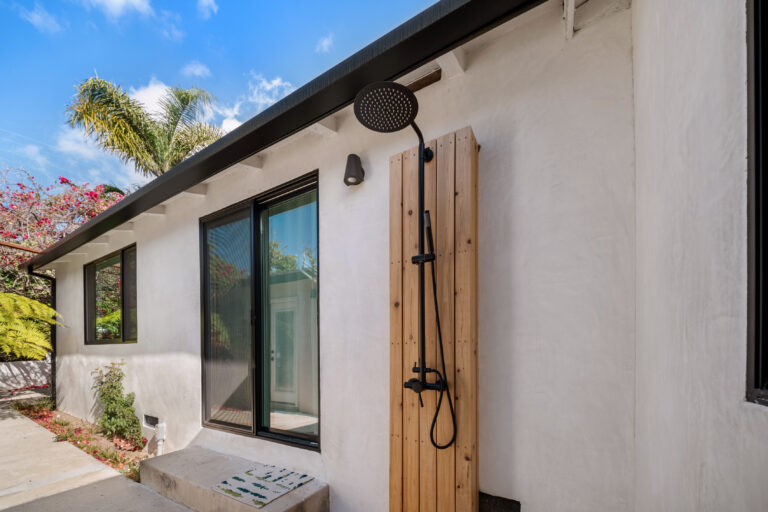 Side Yard Outdoor Shower and Stucco Walls with a black shower head on a wood panel, white stucco and black-framed windows in Manhattan Beach by RnD Builders Inc