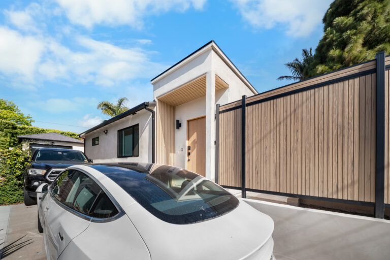 Front Driveway Gate and Covered Entry with a wood-look privacy gate, white stucco and a covered front entry in Manhattan Beach by RnD Builders Inc