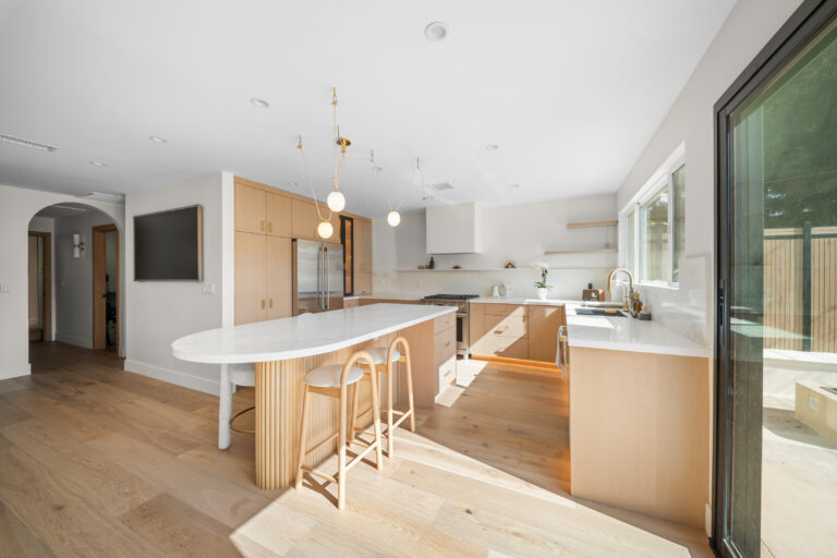 Kitchen Island with Arched Hallway Entry with a white oval island, light oak cabinets and an arched opening to the hall in Manhattan Beach by RnD Builders Inc