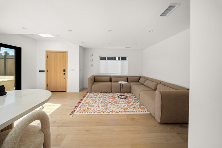 Living Room with L-shaped Sectional with an L-shaped sectional, a patterned area rug and wide-plank flooring in Manhattan Beach by RnD Builders Inc
