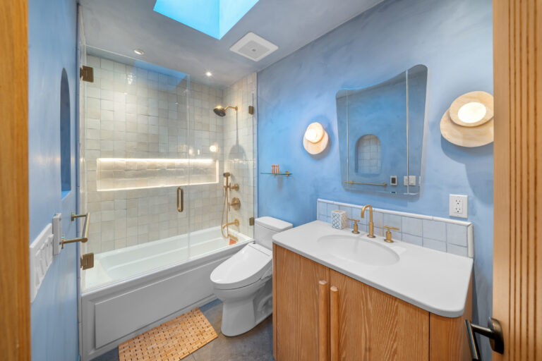 Hall Bathroom with Blue Plaster Walls and Tub-shower with blue plaster-style walls, a skylight, brass fixtures and a glass tub-shower enclosure in Manhattan Beach by RnD Builders Inc