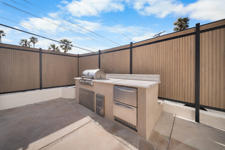 Outdoor Kitchen Along Privacy Fence with a built-in grill counter, tall composite fence and concrete patio in Manhattan Beach by RnD Builders Inc