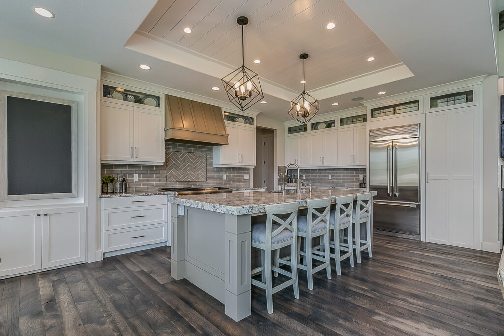 Transitional white shaker kitchen with gray island, herringbone subway tile backsplash, and dark hardwood floors in Camarillo by RnD Builders Inc