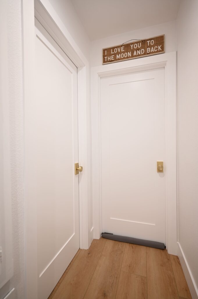 Thousand Oaks complete remodel: Residential hallway with white shaker doors, brass knobs, and light oak hardwood flooring in Thousand Oaks by RnD Builders Inc