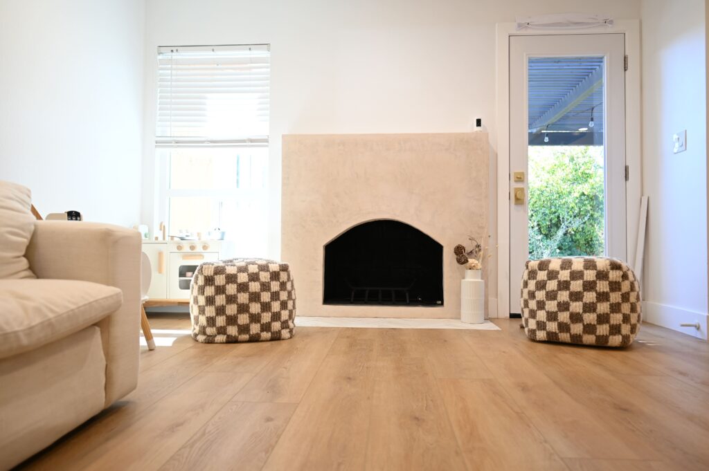 Bright living room with plaster arched fireplace and wide-plank light oak hardwood flooring in Thousand Oaks by RnD Builders Inc