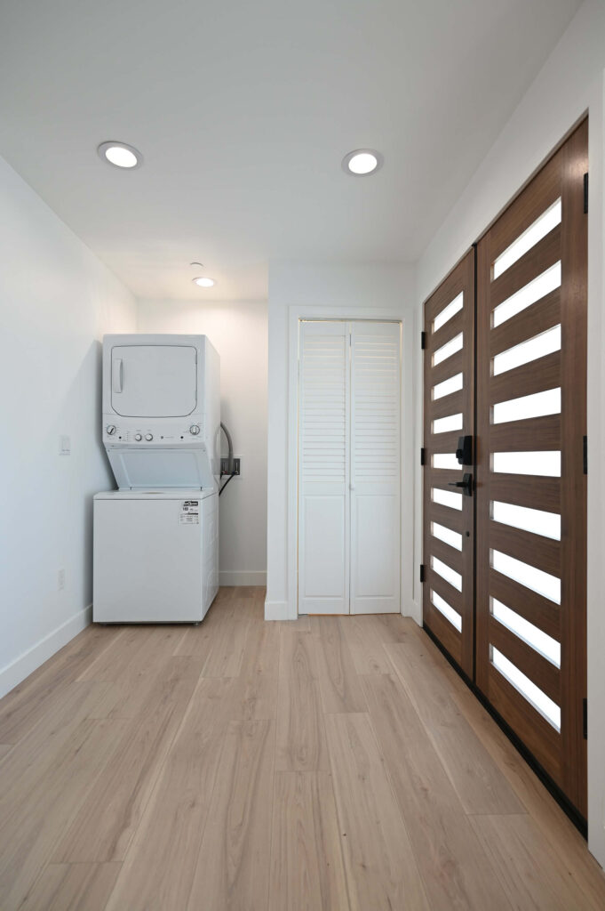 Modern Entryway with Stacked Washer Dryer White Louvered Hawthorne 650 sqft ADU: Hawthorne 650 sqft ADU: Modern entryway with stacked washer dryer white louvered closet and walnut double doors in Hawthorne by RnD Builders Inc