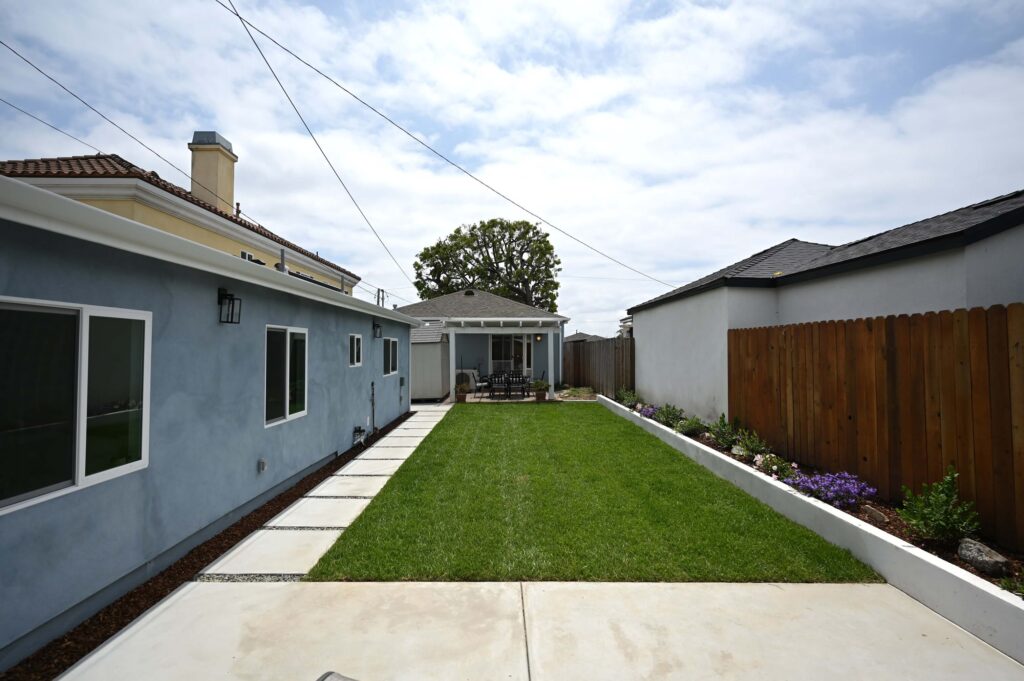 Landscaped Backyard with Green Lawn Landscaped backyard with green lawn, concrete pavers, planter beds, and covered patio ADU by RnD Builders Inc