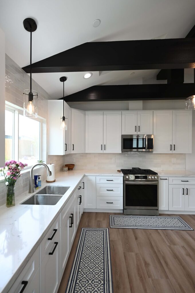 White Shaker Cabinet Kitchen with Black Exposed Beams White shaker cabinet kitchen with black exposed beams, quartz countertops, and stainless appliances by RnD Builders Inc