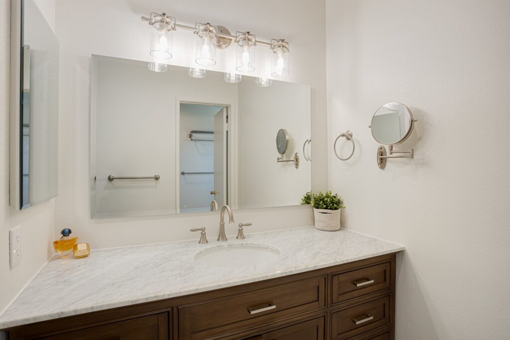 Thousand Oaks bathrooms remodel: Bathroom vanity with dark wood cabinets, marble countertop, and brushed nickel fixtures in Thousand Oaks by RnD Builders Inc