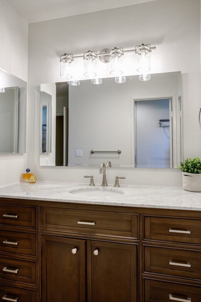 Thousand Oaks bathrooms remodel: Bathroom vanity with dark walnut raised-panel cabinets, marble countertop, and brushed nickel fixtures in Thousand Oaks by RnD Builders Inc