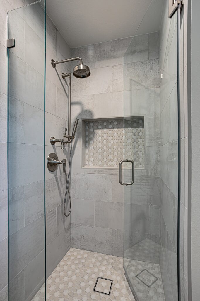 Thousand Oaks bathrooms remodel: Walk-in shower with large-format gray tile, hexagon mosaic niche, and brushed nickel fixtures in Thousand Oaks by RnD Builders Inc