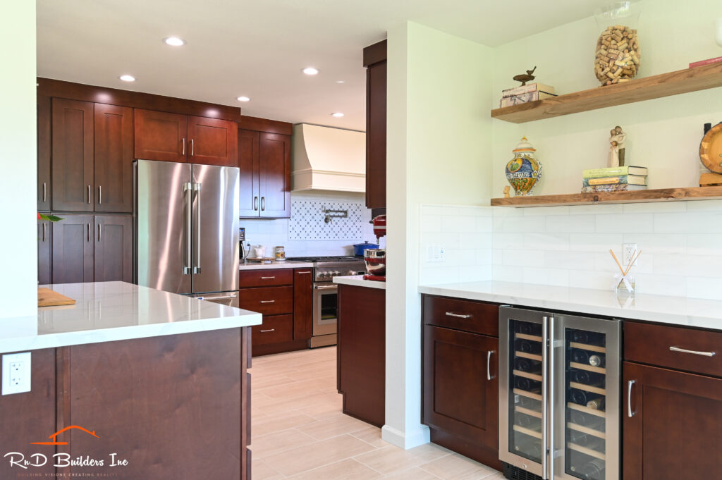 Dark cherry shaker kitchen with white quartz counters, wine cooler, and floating shelves in Westlake Village by RnD Builders Inc