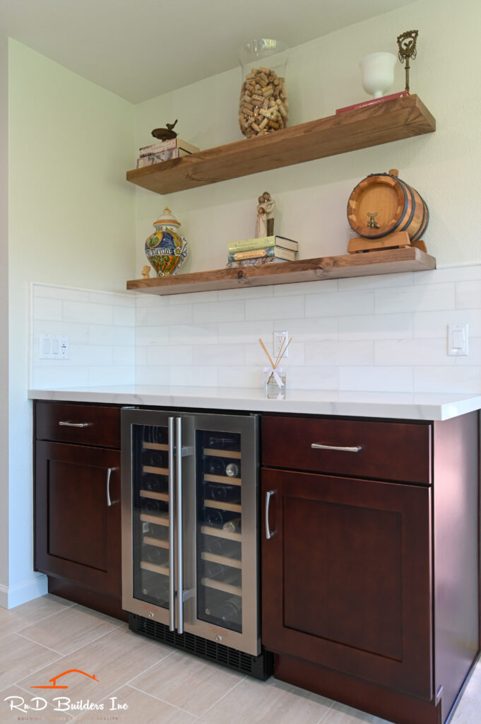 Built-in wet bar with dark cherry shaker cabinets, wine cooler, white quartz countertop, and floating wood shelves in Westlake Village by RnD Builders Inc