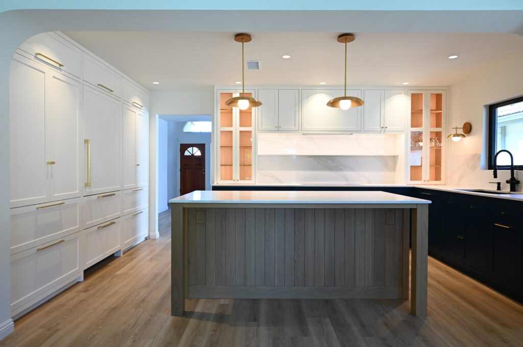 Transitional kitchen with gray shiplap island, navy lower cabinets, white uppers, and brass pendant lights by RnD Builders Inc