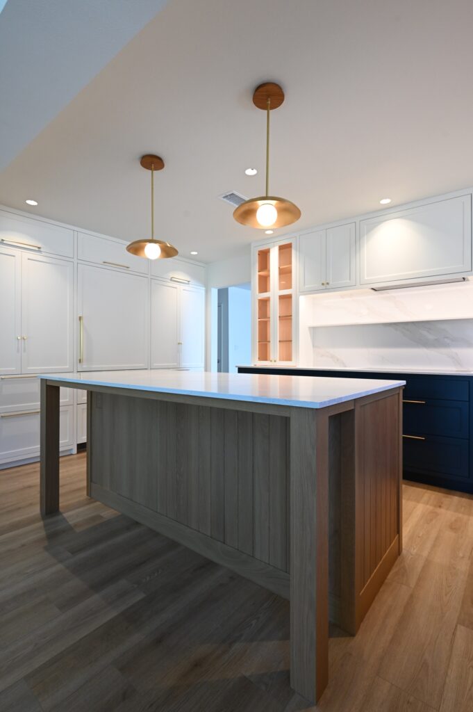 Open Kitchen with Gray Wood Island Open kitchen with gray wood island, navy lower cabinets, white uppers, and brass pendant lights by RnD Builders Inc