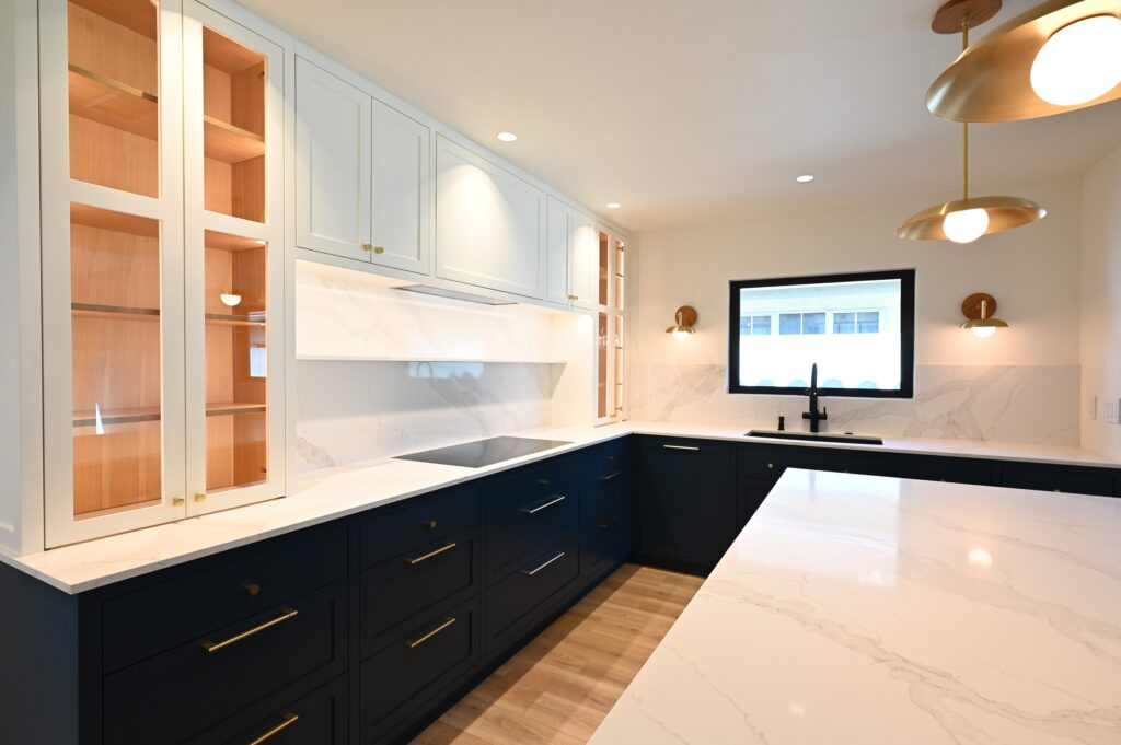 Los Angeles custom kitchen: Two-tone kitchen with navy shaker base cabinets, white upper glass-front cabinets, and quartz countertops in Los Angeles by RnD Builders Inc