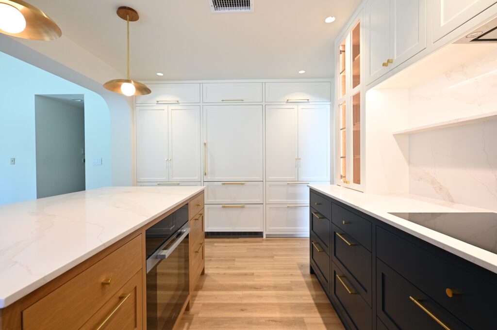 Transitional kitchen with white shaker cabinets, navy lower cabinets, oak island, and brass hardware by RnD Builders Inc