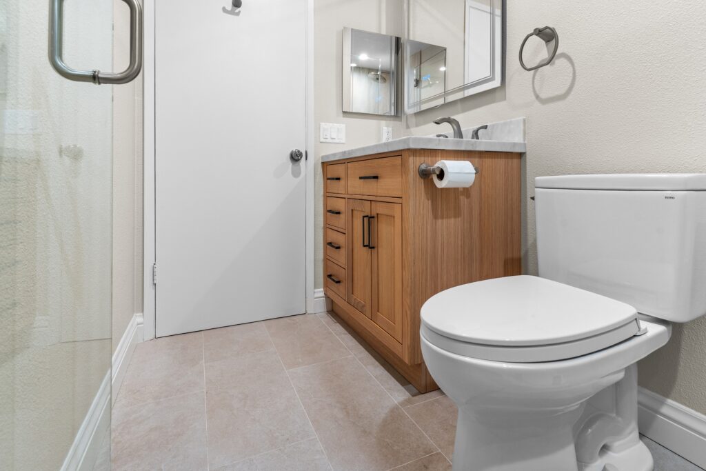 Thousand Oaks full remodel: Remodeled bathroom with warm wood shaker vanity, marble countertop, and TOTO toilet in Thousand Oaks by RnD Builders Inc