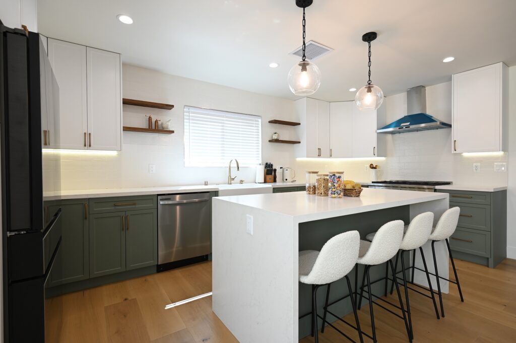 West Hills Full Remodel Remodeling in West Hills: Two-tone kitchen with sage green lower cabinets, white uppers, quartz island, and globe pendants by RnD Builders Inc