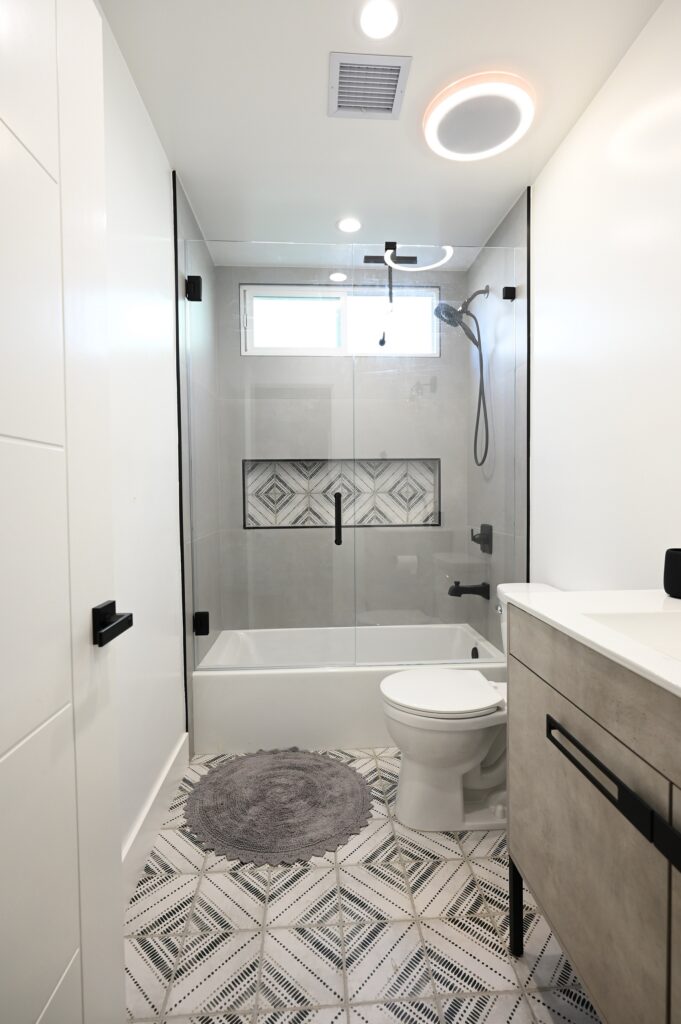 West Hills full remodel: Modern bathroom remodel with geometric floor tile, glass shower enclosure, and soaking tub in West Hills by RnD Builders Inc