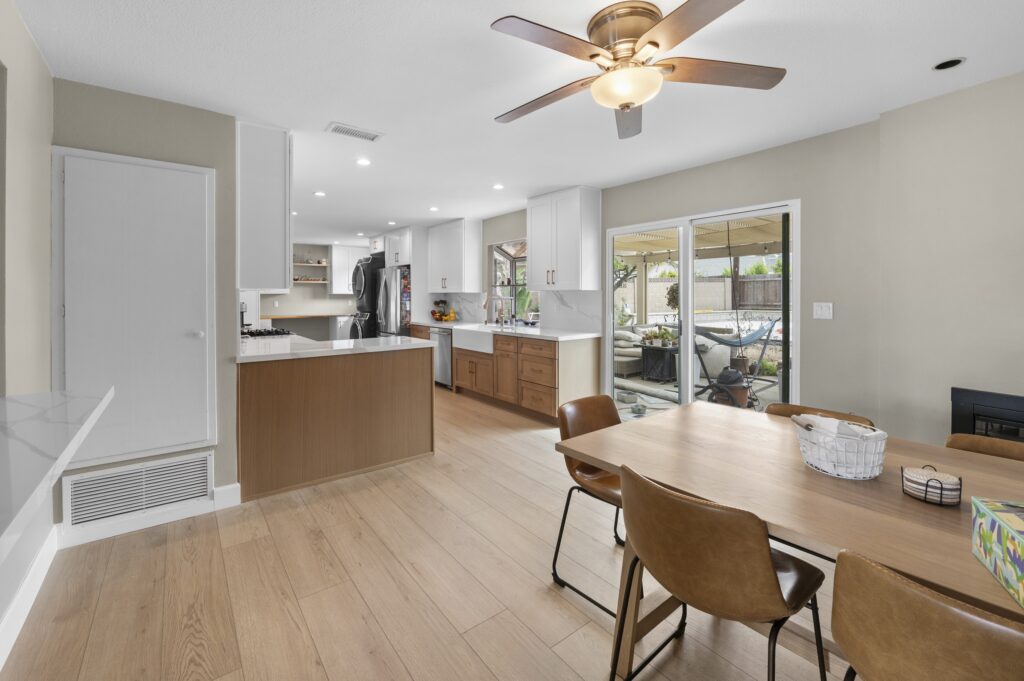 Open-concept Kitchen and Dining Area Open-concept kitchen and dining area with white shaker cabinets, walnut lower cabinets, quartz countertops, and light oak hardwood flooring by RnD Builders Inc