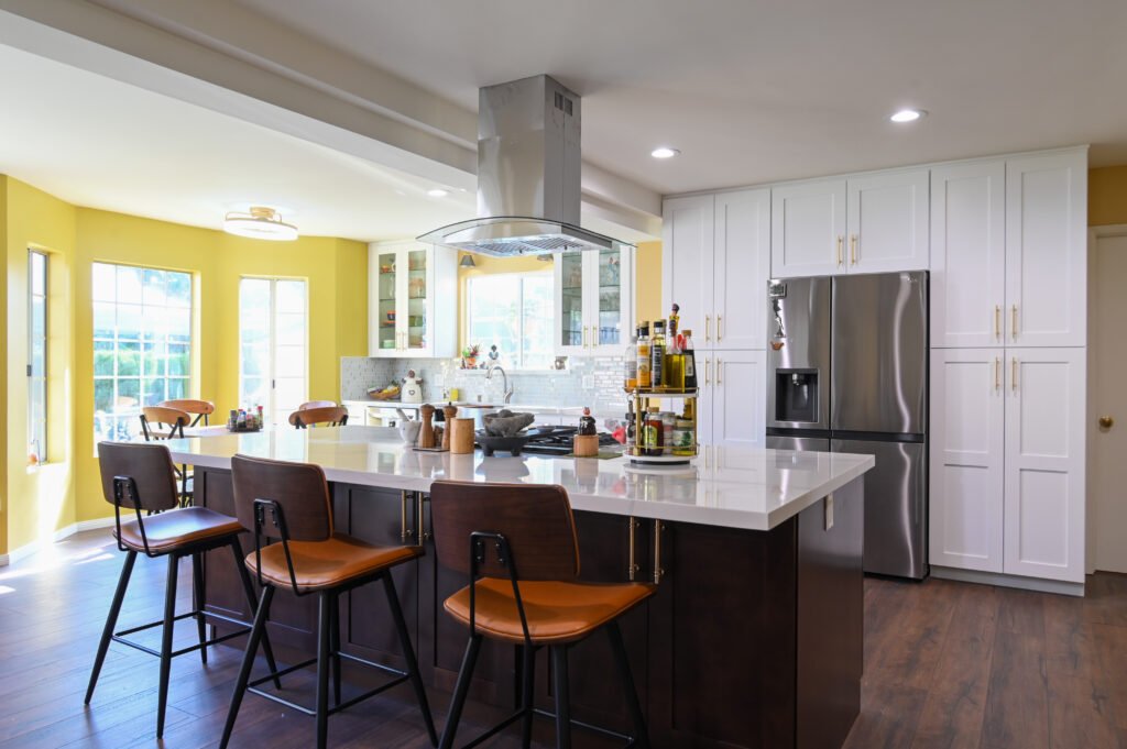 Los Angeles kitchen remodel: Open-concept kitchen with dark wood island, white shaker cabinets, and stainless island hood in Los Angeles by RnD Builders Inc