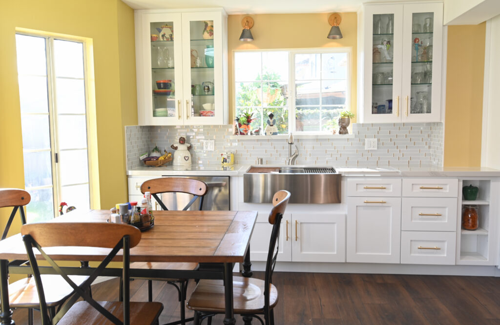 Bright Kitchen with White Shaker Cabinets Bright kitchen with white shaker cabinets, stainless farmhouse sink, and yellow walls by RnD Builders Inc
