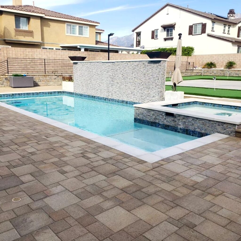 Geometric Backyard Pool and Spa in Los Angeles Geometric backyard pool and spa with stone waterfall wall and paver deck in Los Angeles by RnD Builders Inc