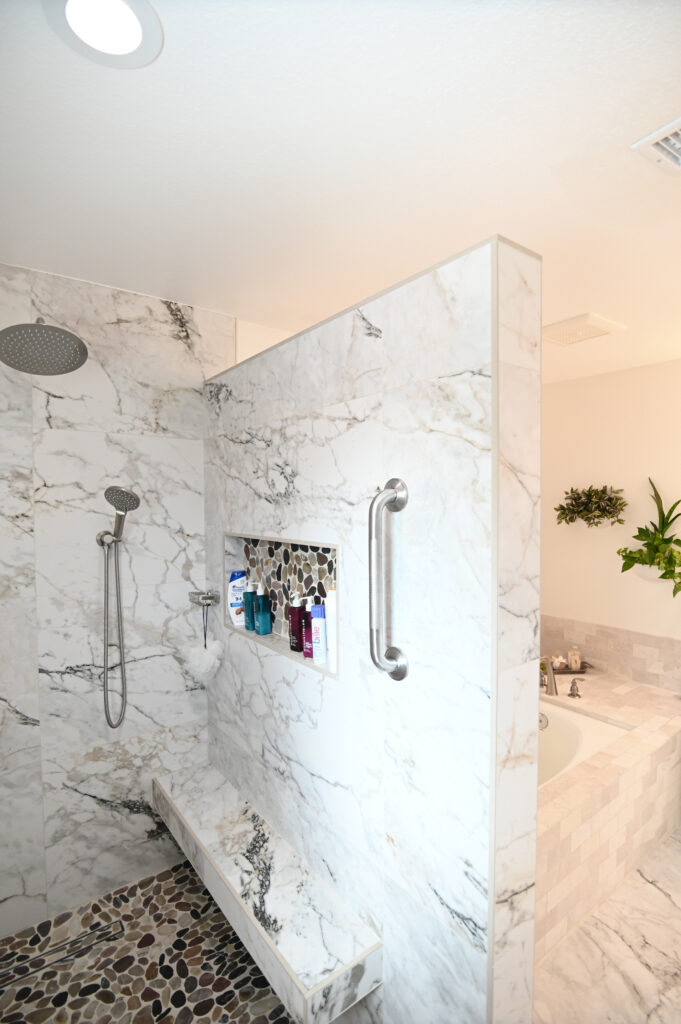 Moorpark bathroom remodel: Walk-in shower with marble tile walls, pebble stone floor, rain showerhead, and built-in niche in Moorpark by RnD Builders Inc